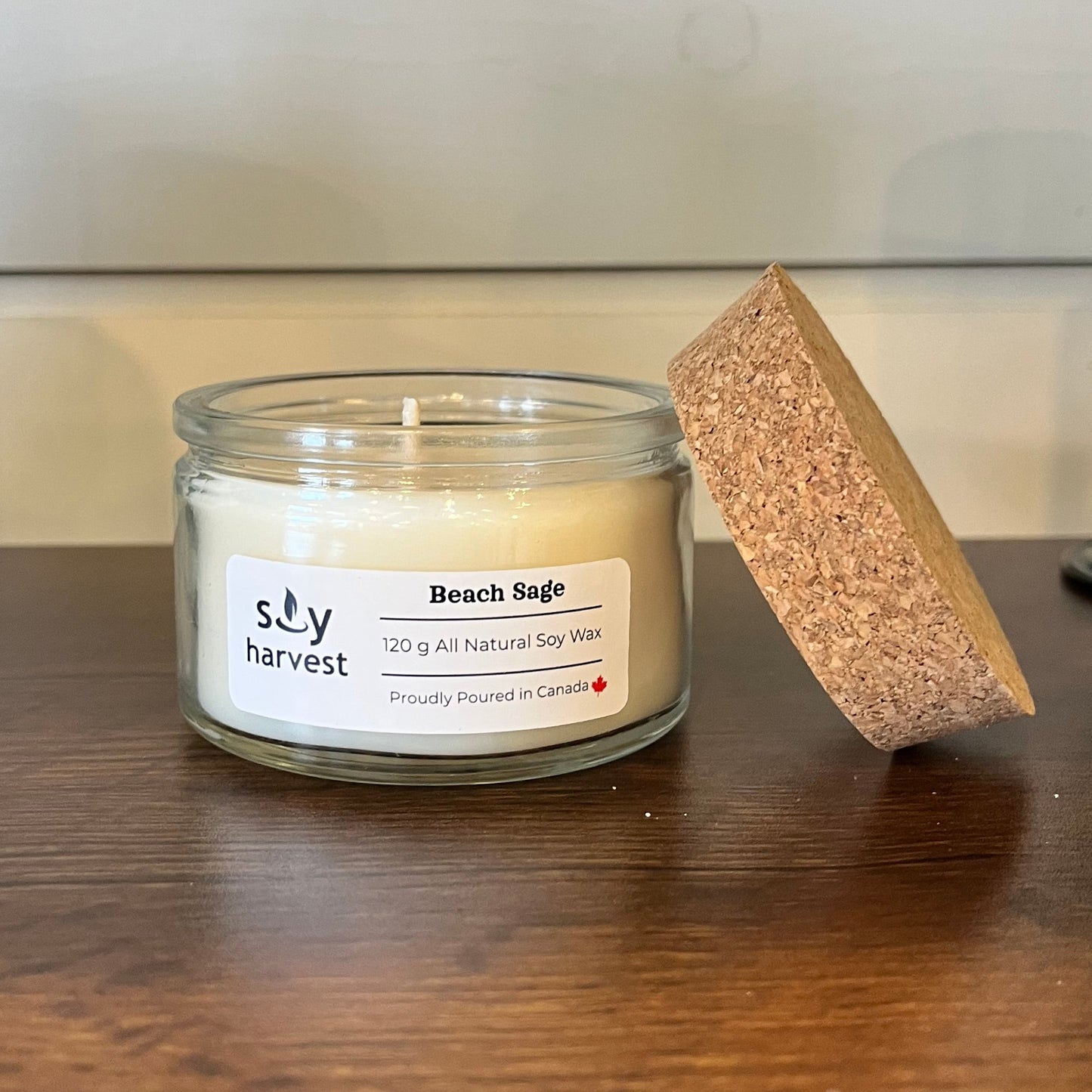 Candle in a glass jar with a label on a wooden surface,