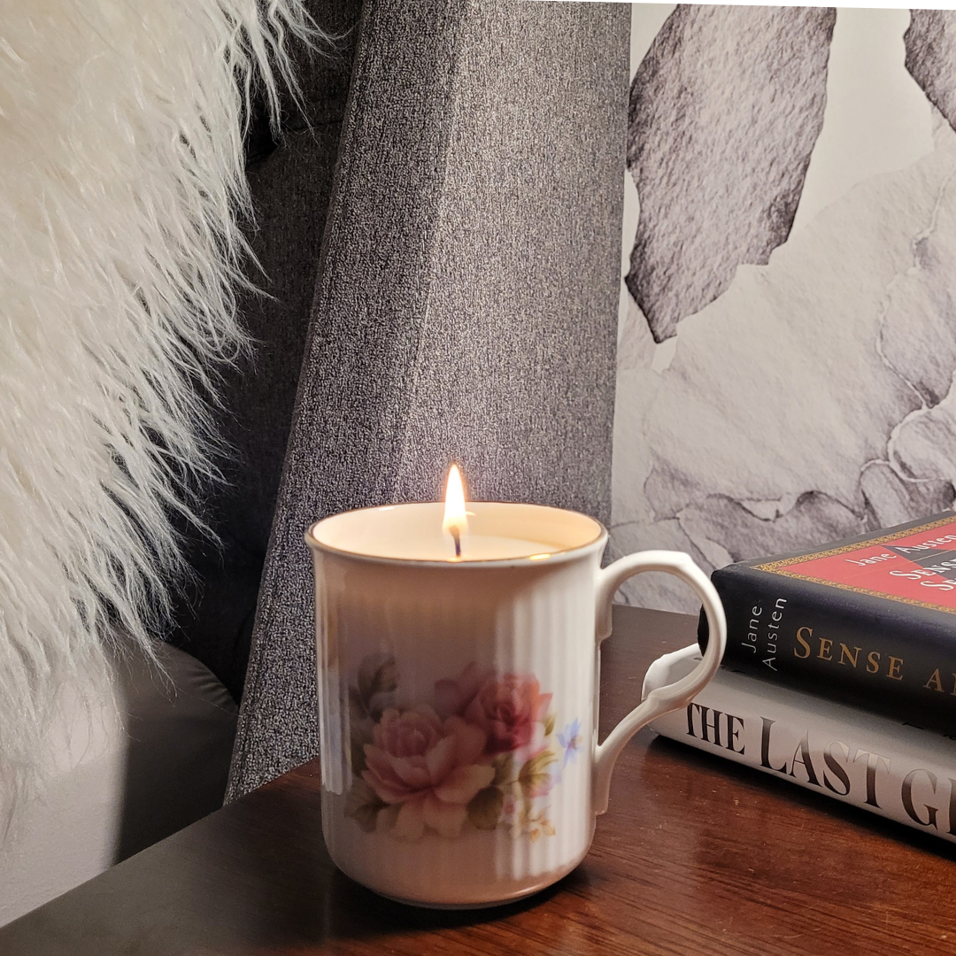 candle in teacup on nightstand lit.