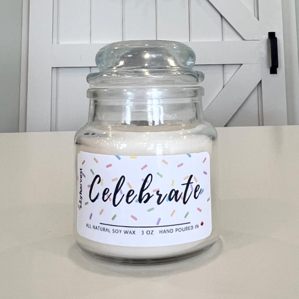 Glass jar candle with a 'Celebrate' label on a white surface.
