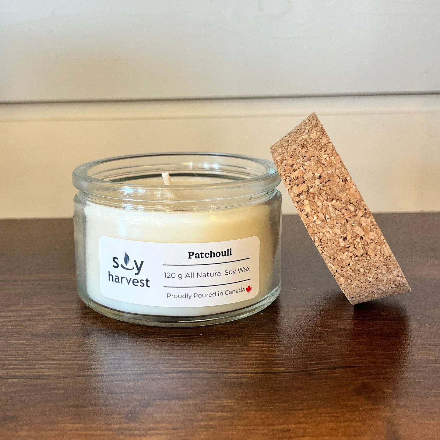Small glass candle jar with cork lid on a wooden surface
