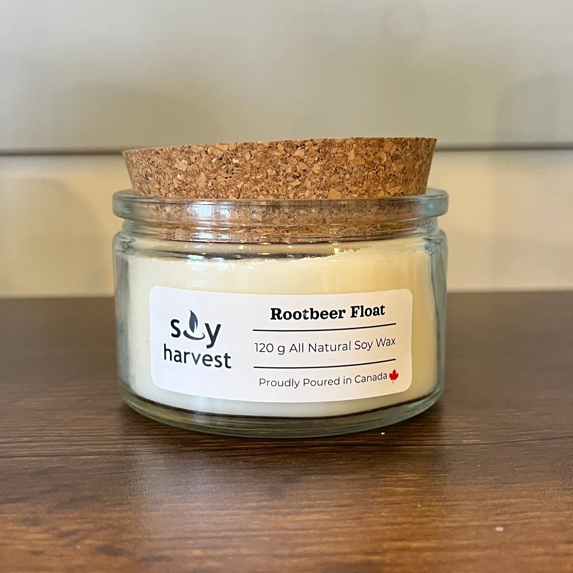 Soy Harvest Rootbeer Float candle in a glass jar with a cork lid on a wooden surface.
