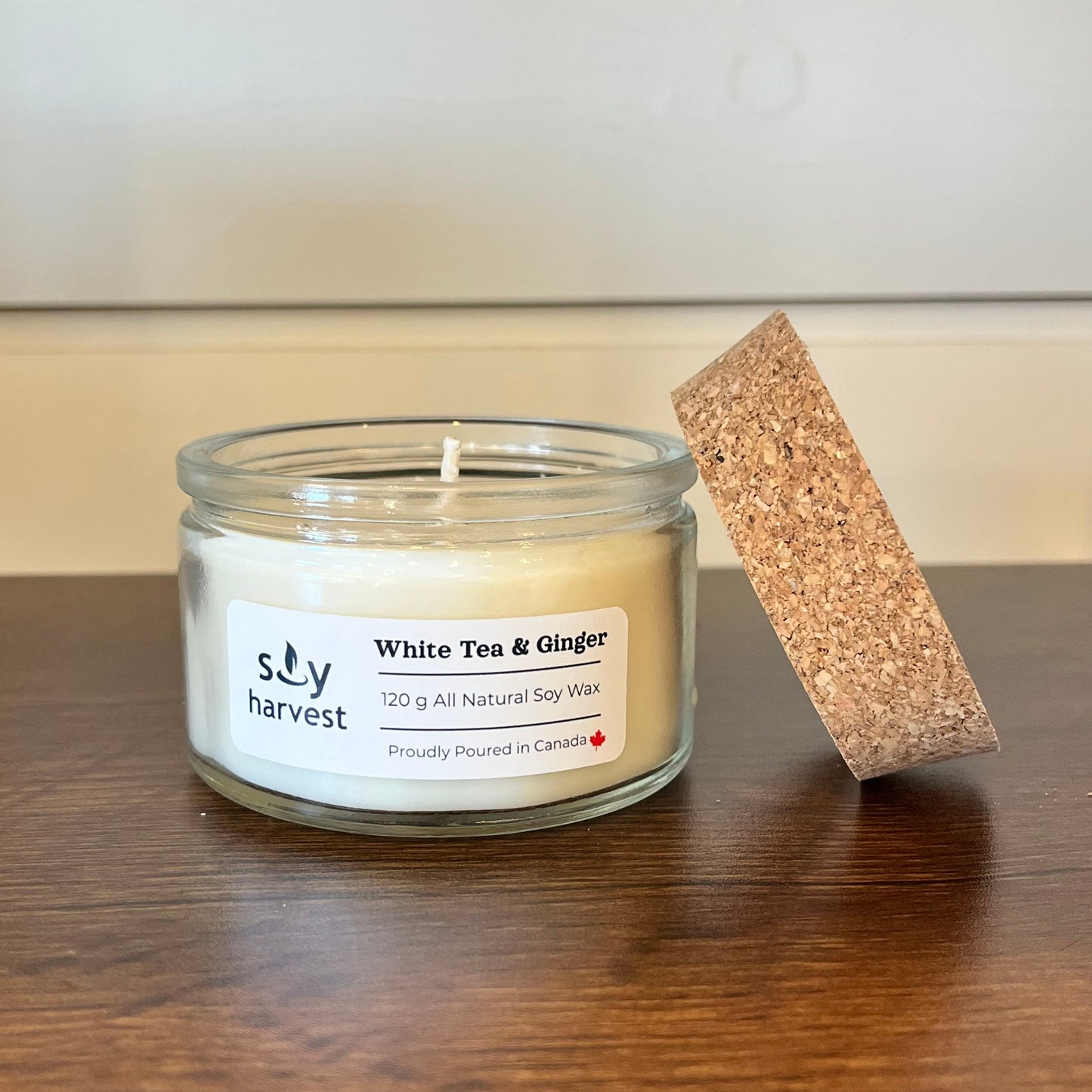 Candle in a glass jar with a cork lid on a wooden surface